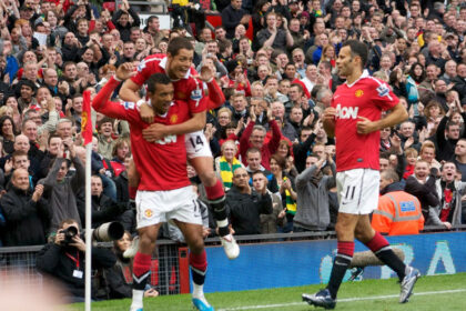 Chicharito salta sobre la espalda de Nani, con Ryan Giggs a la derecha, durante un festejo de Manchester United en 2010
