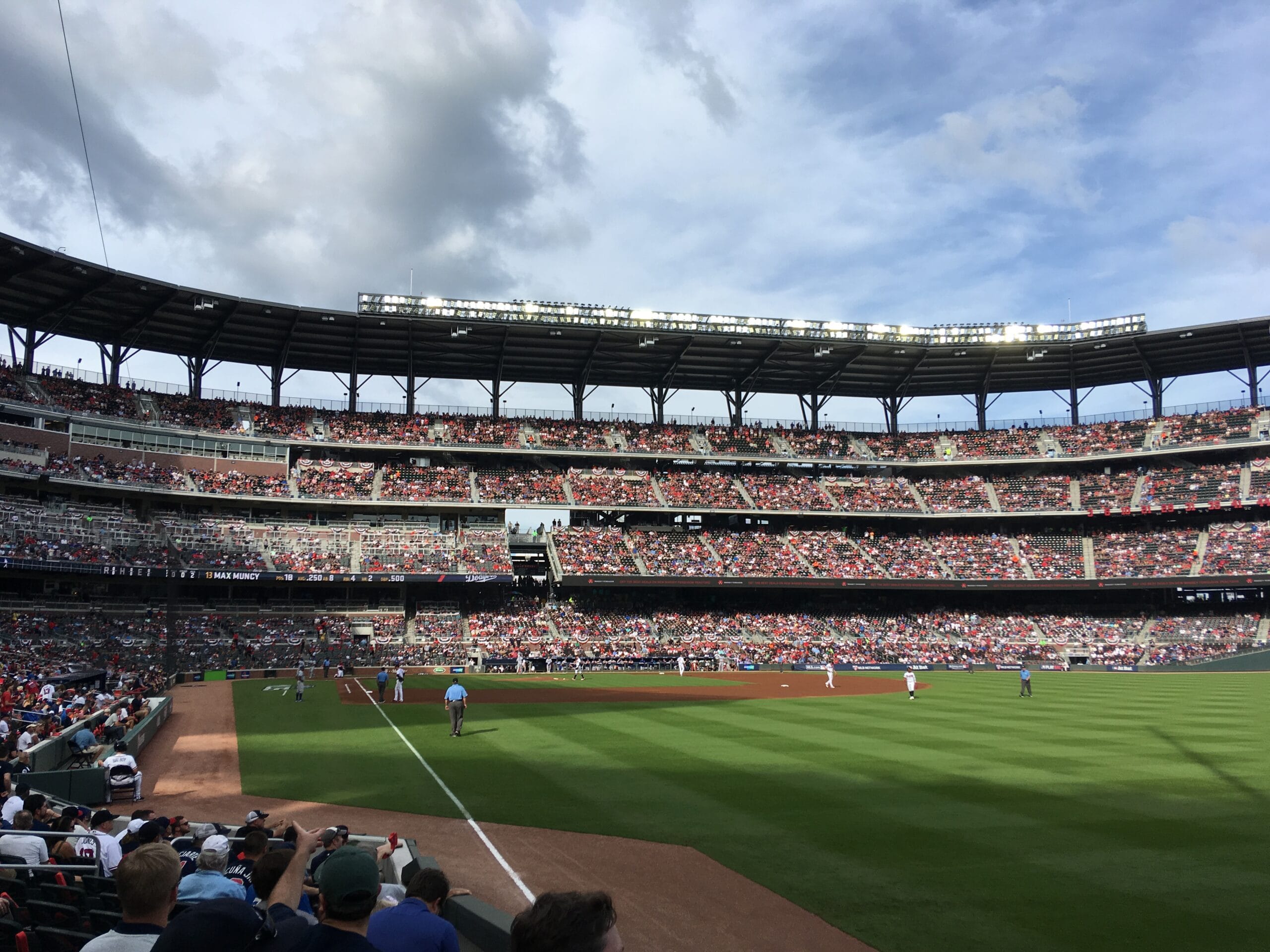 Jugadores de Dodgers y Braves en el diamante durante el Juego 4 de la Serie Divisional de 2018, frente a tribunas llenas.