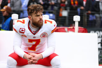 Harrison Butker, con el uniforme blanco número 7 de Kansas City Chiefs, sentado en la banda en enero de 2024