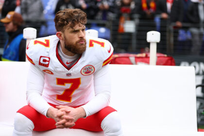 Harrison Butker, con el uniforme blanco número 7 de Kansas City Chiefs, sentado en la banda en enero de 2024