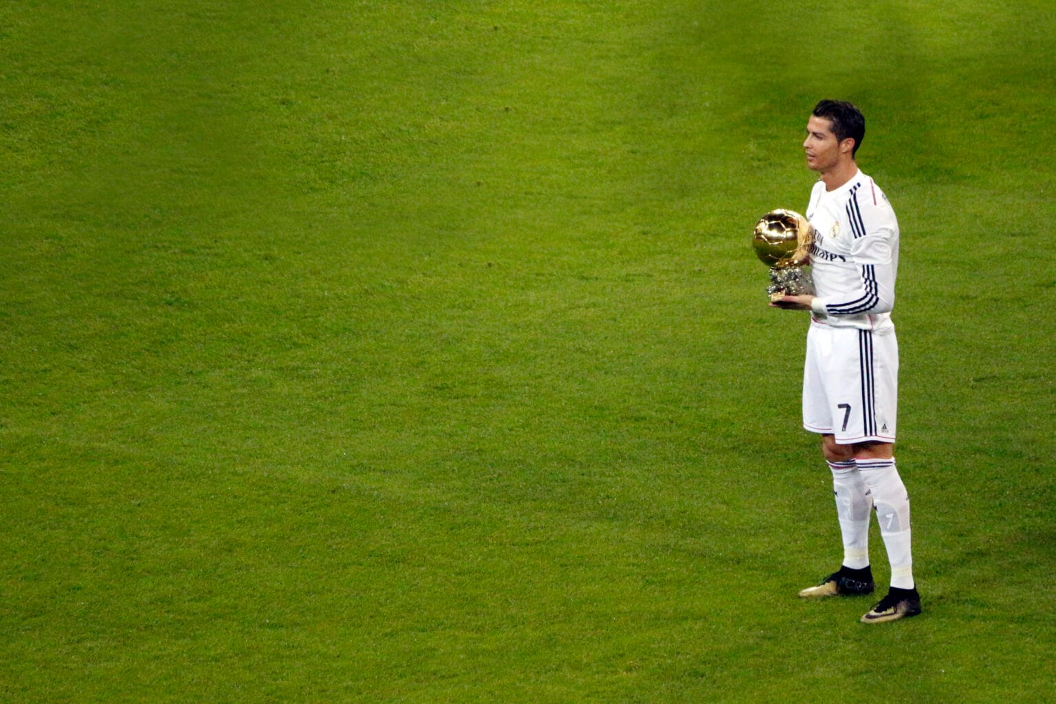 Cristiano Ronaldo sostiene su Balón de Oro de 2014 sobre el césped del Santiago Bernabéu